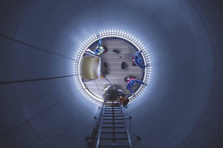 top down internal view of tank with ladder and three men working